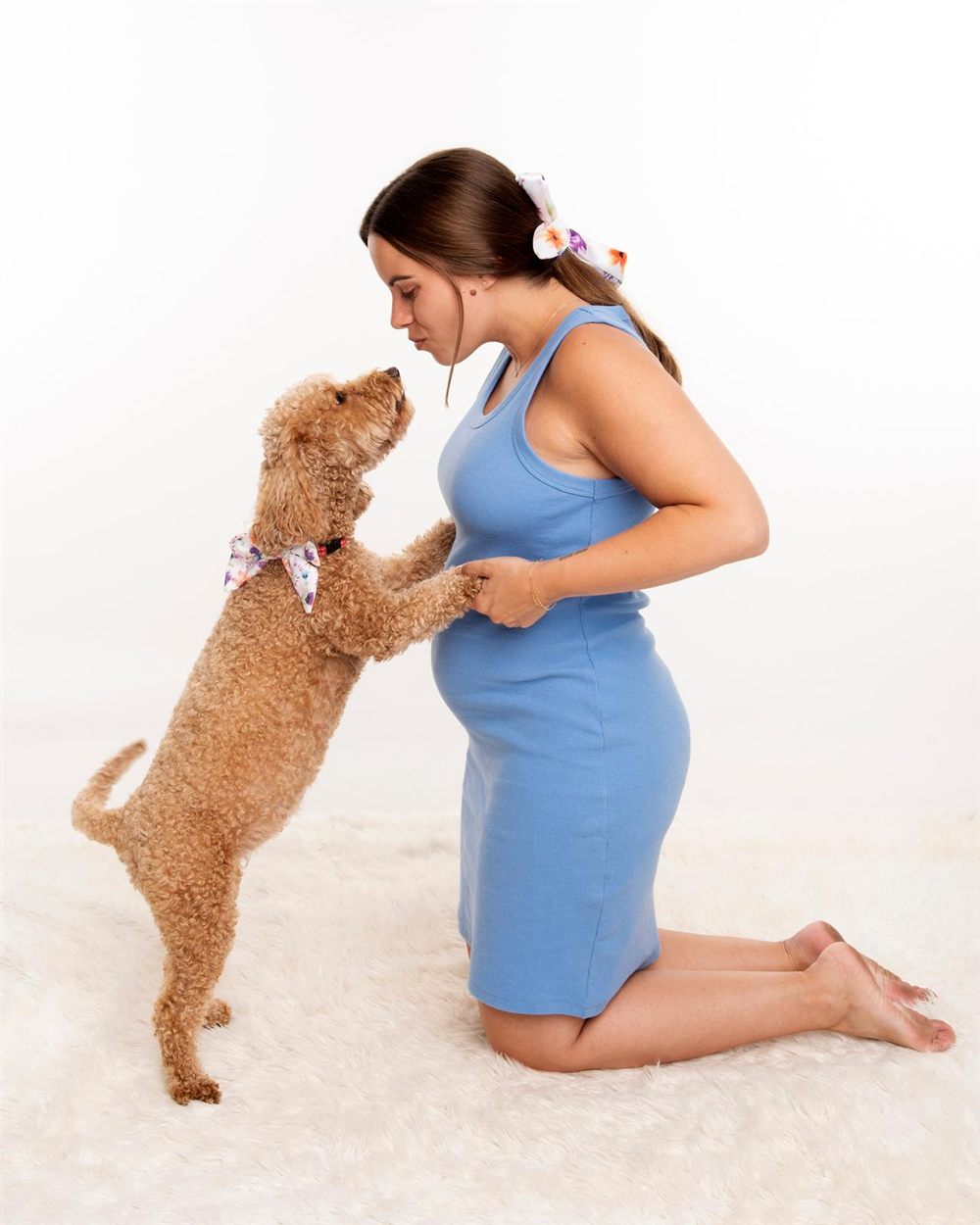 Jess kneeling on a white rug holding Lucille's paws as Lucille stands up to greet her